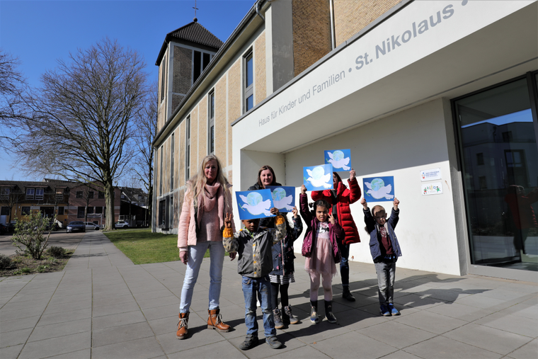 Kinder zeigen selbstgebastelte Friedenstauben